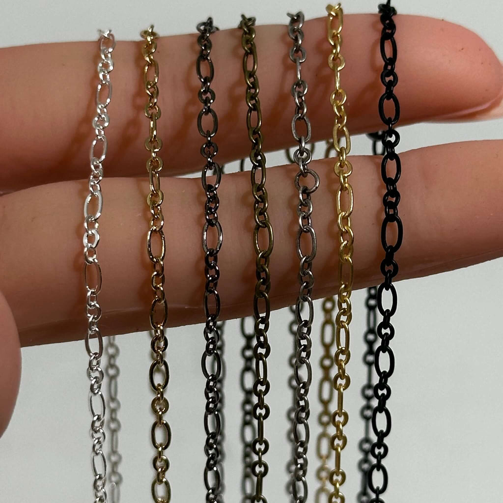 Alternating links cable chain for jewelry making in silver, gold, gunmetal, brass antique silver, matte gold and matte black being held in a hand to show the size. 